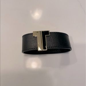 Tory Burch black leather bracelet with the “T” in black and gold.